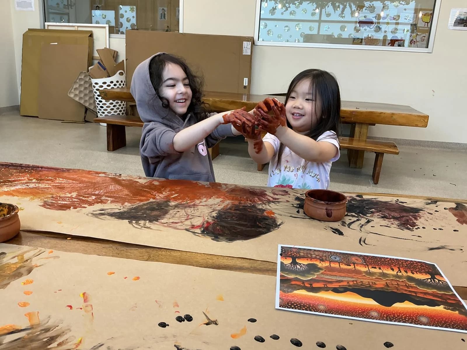 Two children with clay-covered hands at a painting table at a Simba Education Sydney early learning centre