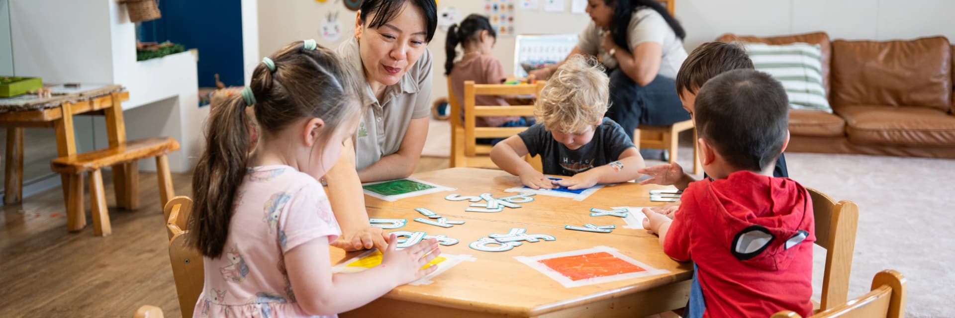 Educator and preschoolers at a literacy table at a Simba Education Sydney early learning centre